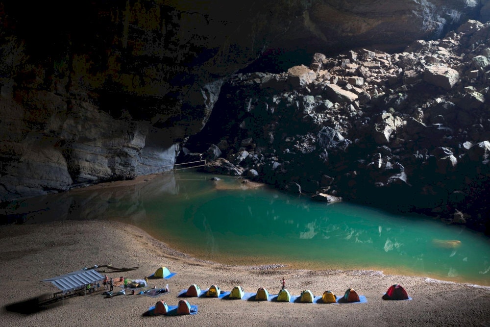 The expedition team sets up camp beside a tranquil underground river under Son Doong’s colossal ceiling